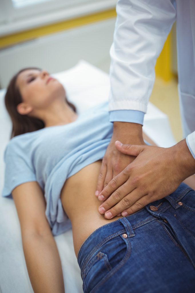 Doctor examining the stomach of a female patient