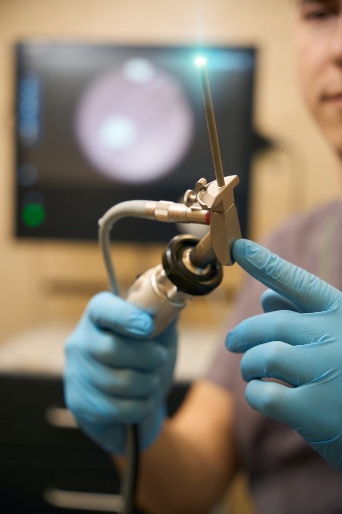 Doctor inspecting medical instrument before anoscopy procedure