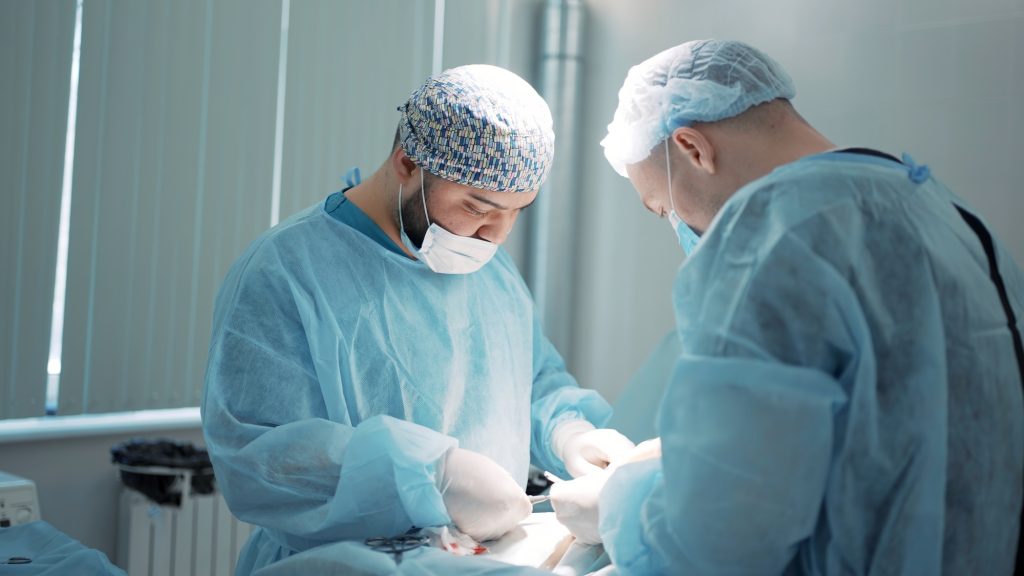The concept of medicine . Action . Male surgeons in special special clothes, blue robes, gloves