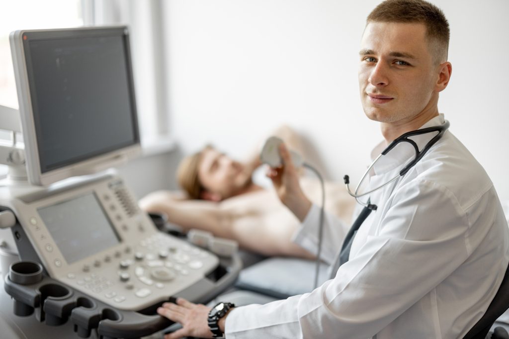 Ultrasound specialist examining lower abdomen of male patient